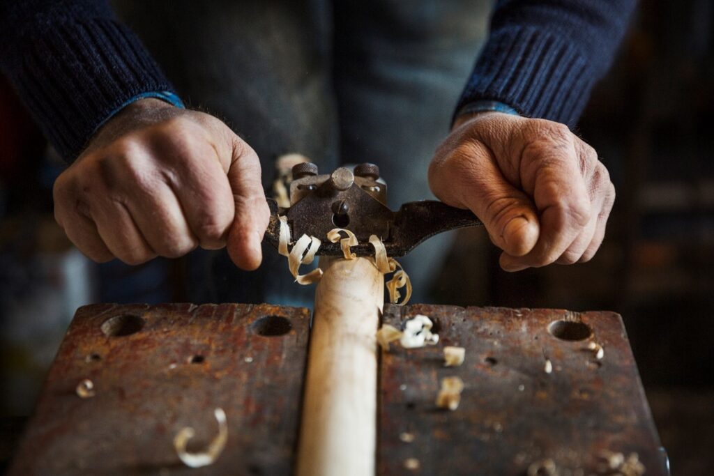 Person shaving a piece of wood